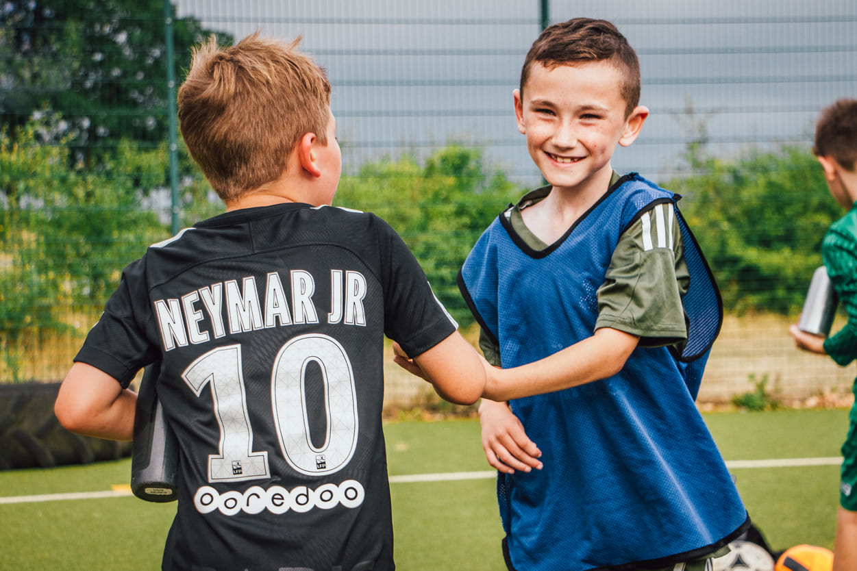 Kids football huddle showing teamwork and social connection at a We Make Footballers academy.